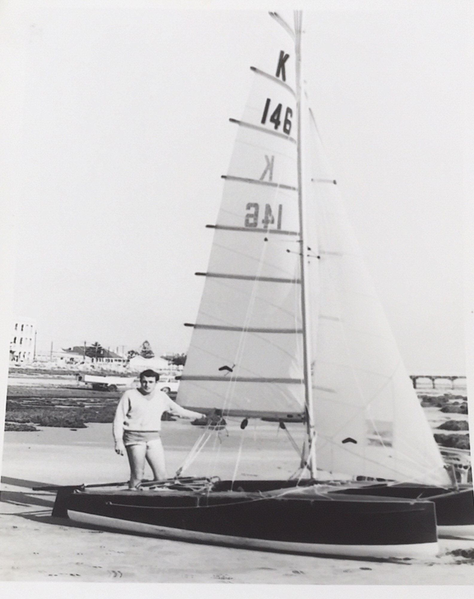 Bob Newmarch standing beside a Paper Tiger catamaran on the beach