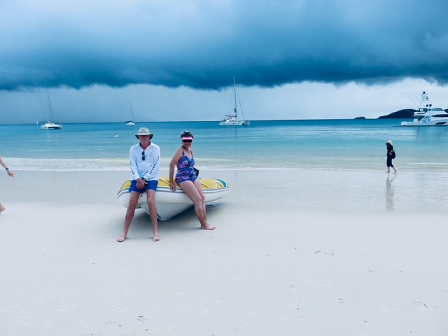 Bob and his partner seated on a dinghy at the beach